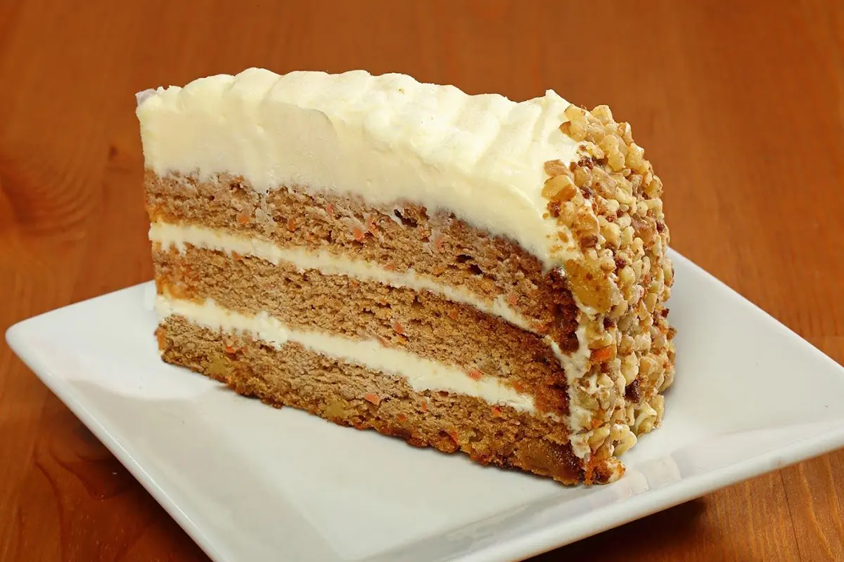 A piece of carrot cake with white frosting on top.