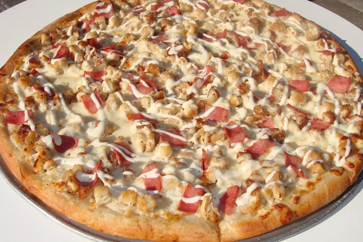 A pizza with bacon, chicken and cheese on it.